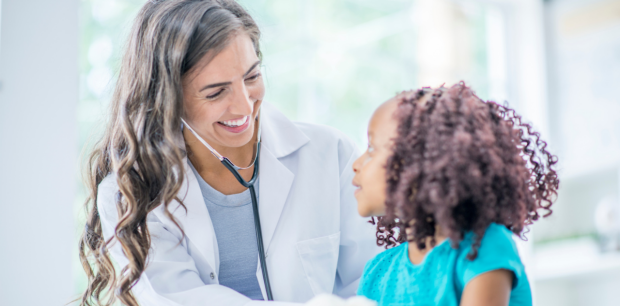 Female pediatrician with long hair using a stethoscope on a child with curly hair